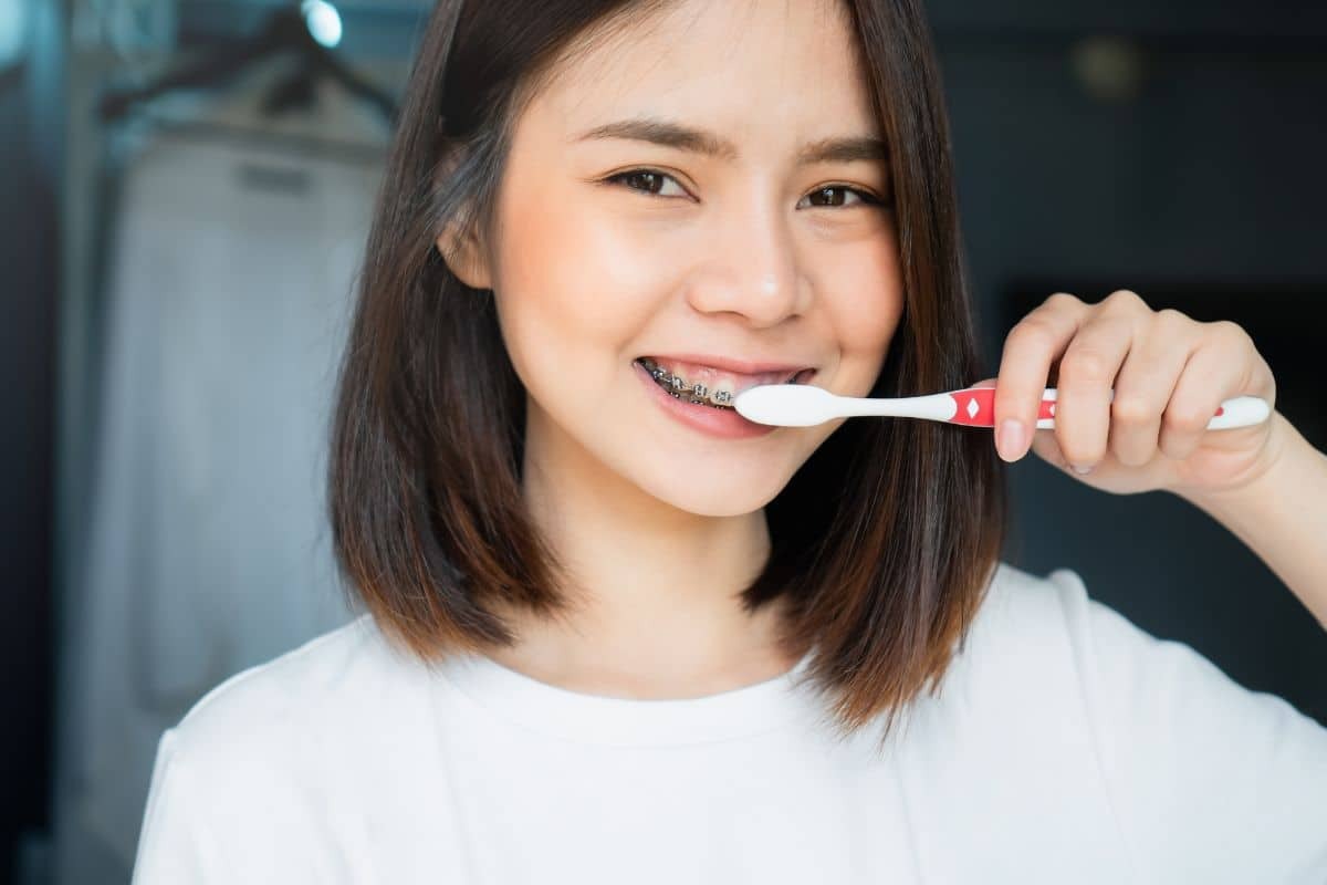A teen brushing teeth with braces using a toothbrush.
