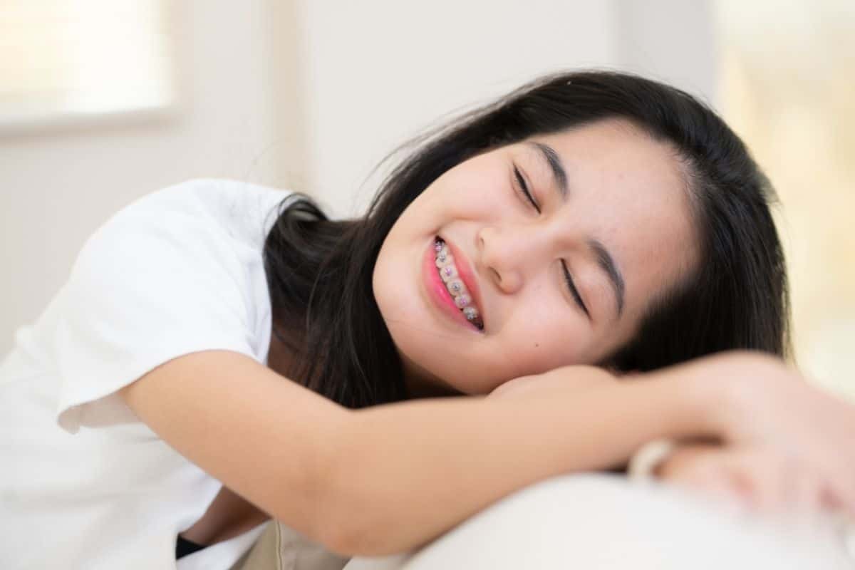 Smiling young woman with braces resting peacefully.
