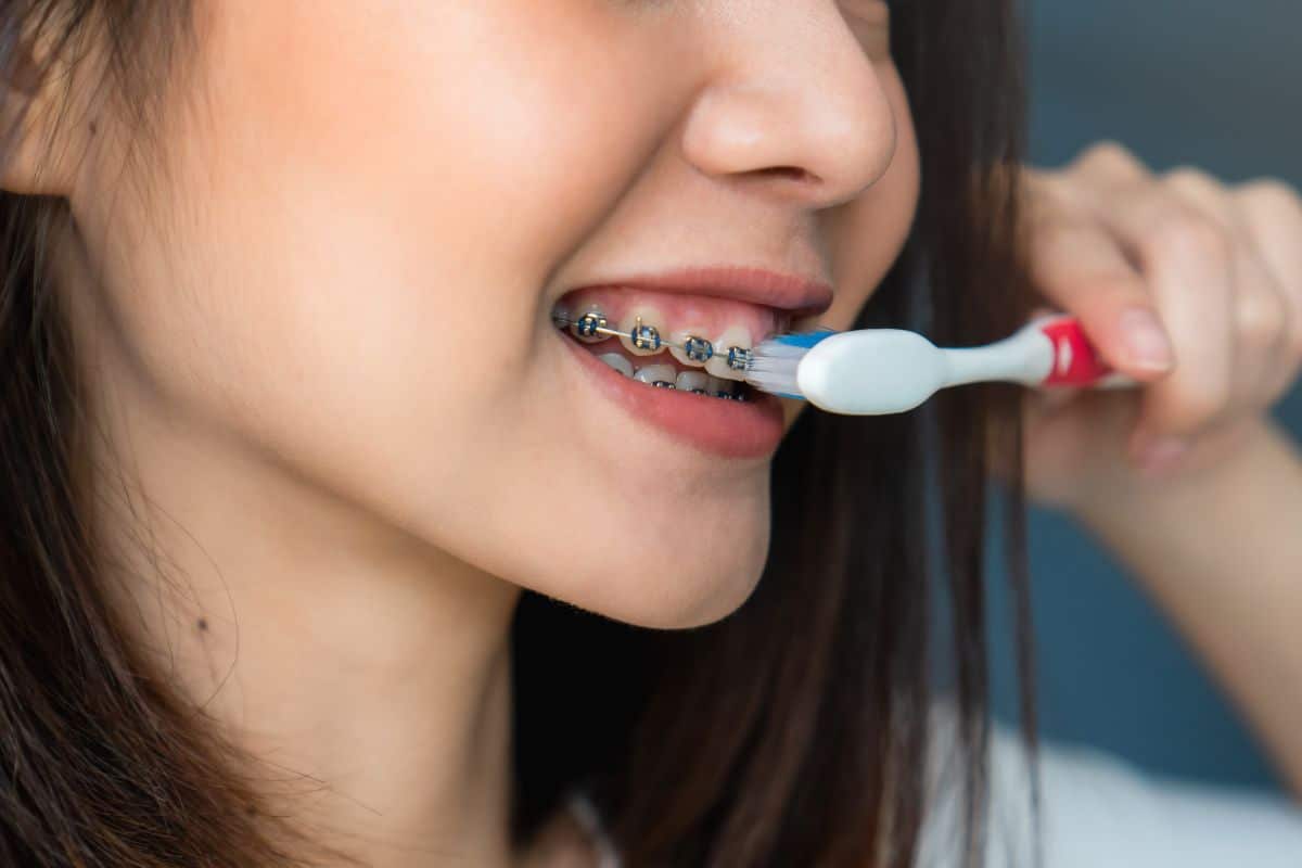 Teen brushing teeth with braces guided by an orthodontist.