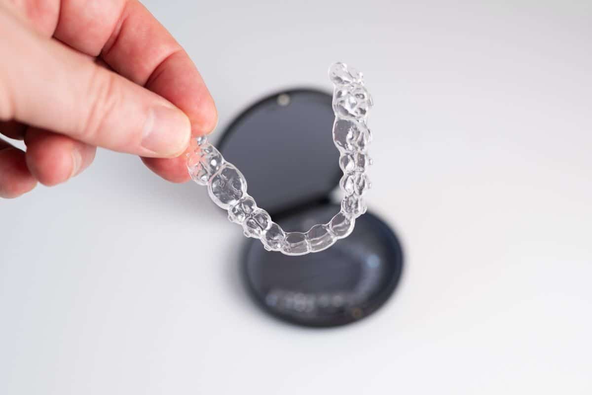Clear Invisalign aligner held by hand, showing a discreet orthodontic solution for correcting dental alignment issues.