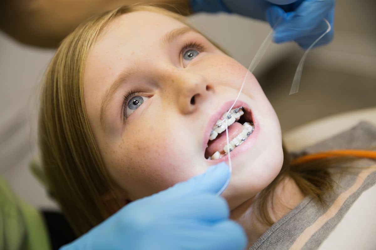 Child receiving early orthodontic treatment with braces adjustment during dental visit.