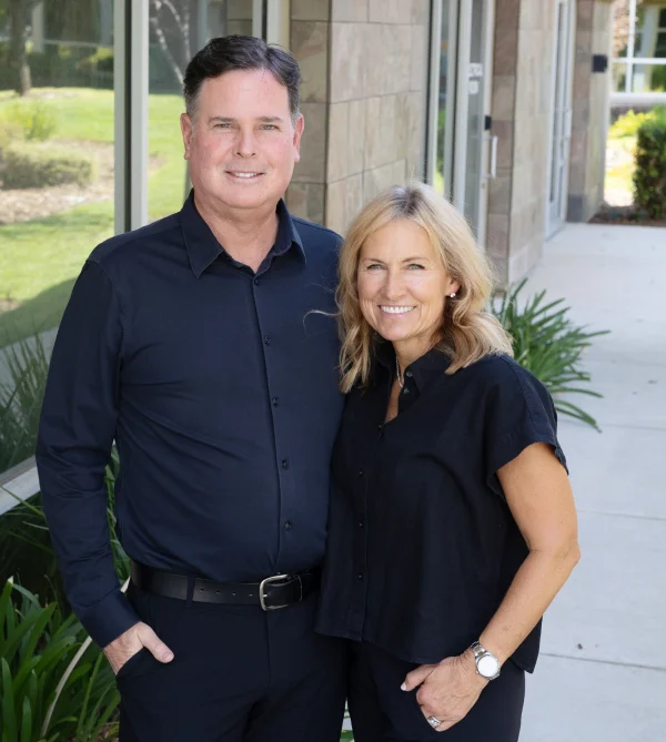 Smiling man and woman in black standing outside an office building